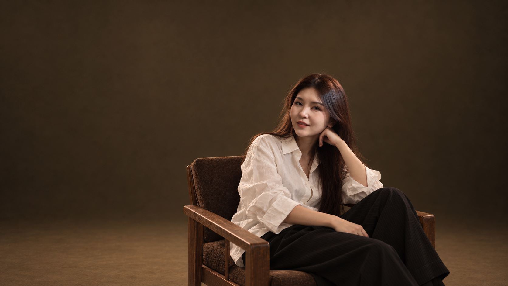 Portrait of Mila seated against a warm brown studio background